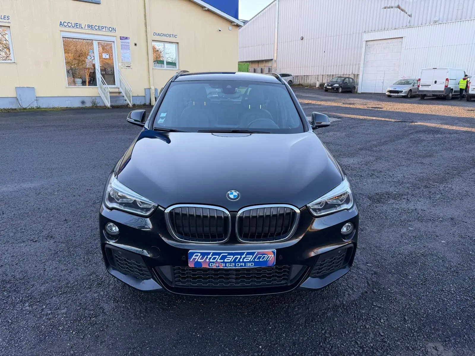 Vue avant d'un BMW X1 noir métal 2018 avec calandre double haricot et phares LED, sur parking extérieur.