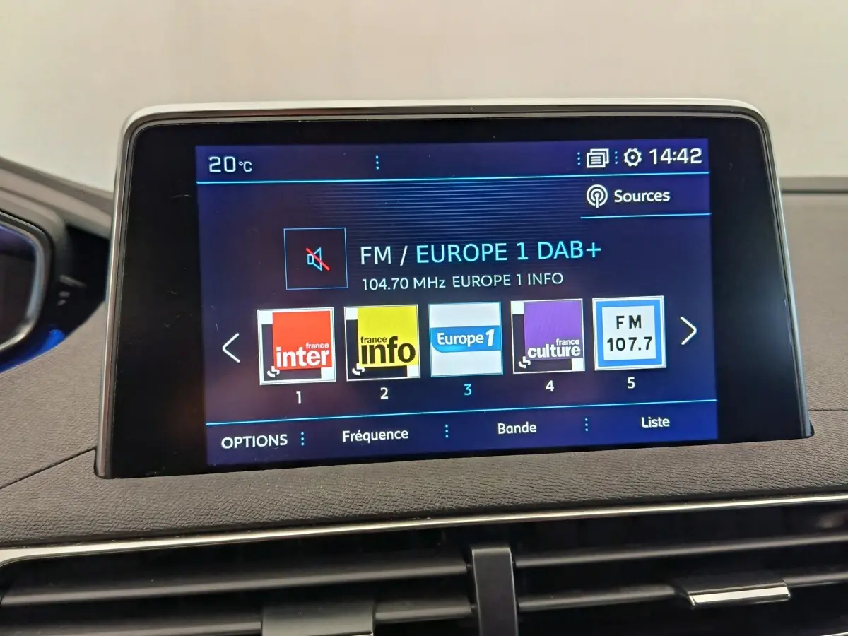 Écran tactile central affichant les stations radio dans l'habitacle du Peugeot 5008 gris foncé, vue intérieure frontale.