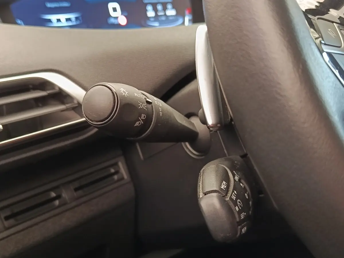 Gros plan sur la commande des phares et du régulateur de vitesse côté gauche du volant d’un Peugeot 5008 gris foncé 2020.