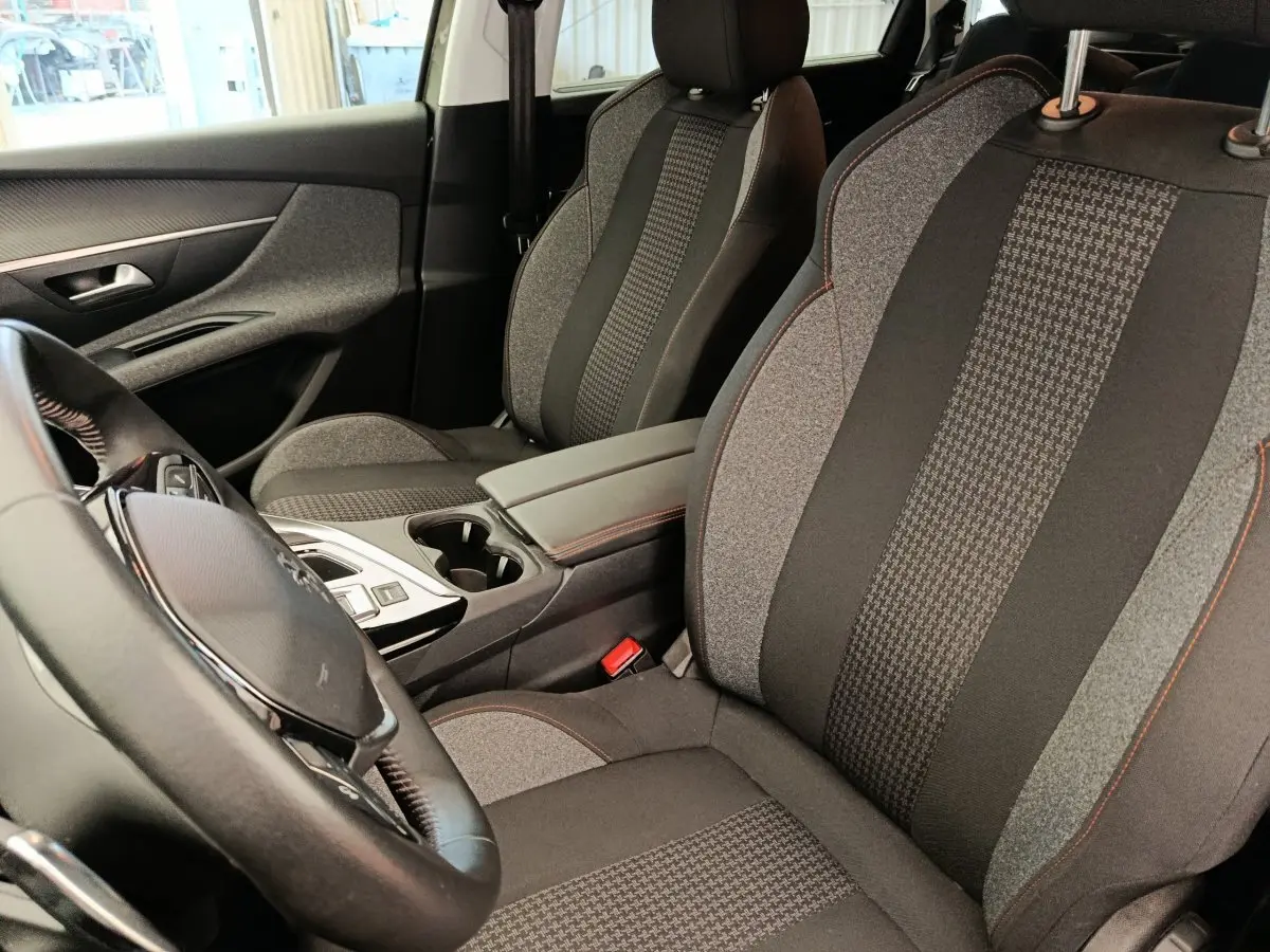 Vue intérieure côté conducteur du Peugeot 5008 2020, sièges tissu gris à motifs et volant cuir noir.