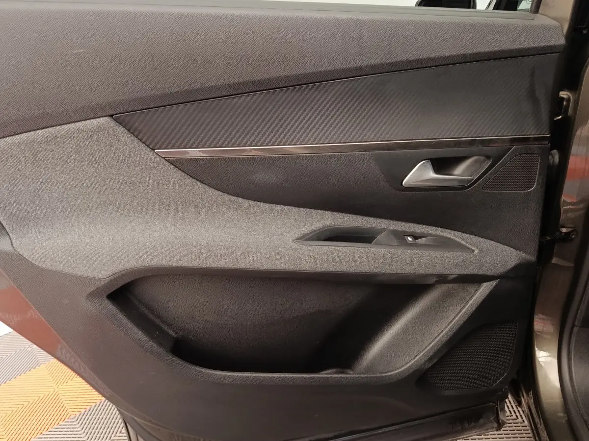 Vue intérieure côté droit de la porte avant grise du Peugeot 5008 avec habillage tissu et plastique noir.
