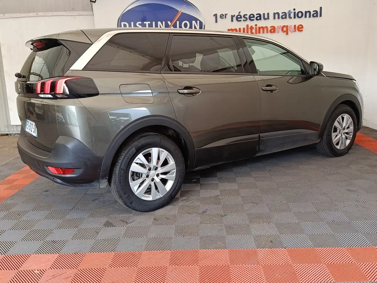Peugeot 5008 gris foncé en vue 3/4 arrière droit, avec feux arrière à griffes rouges distinctifs.