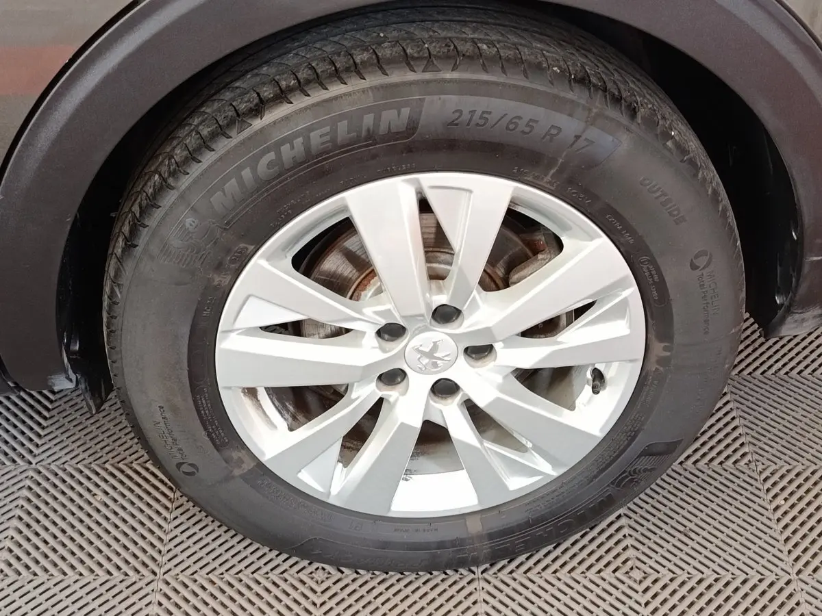 Gros plan sur la roue avant droite d’un Peugeot 5008 gris foncé, avec jante alliage et pneu Michelin.