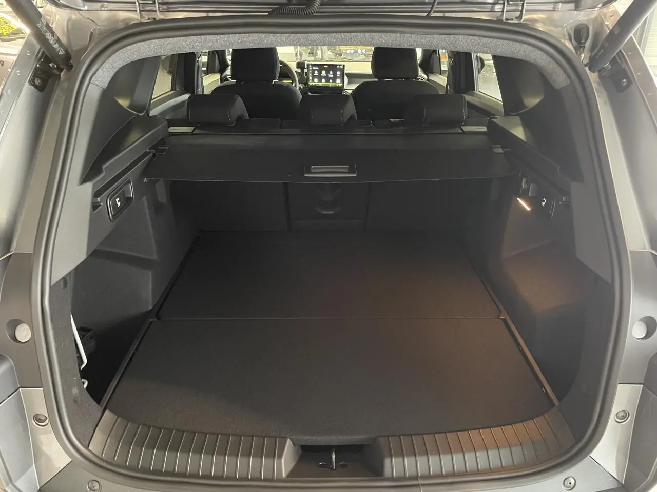 Coffre ouvert vu de l'arrière du Dacia Bigster gris schiste, avec banquette arrière et tablette cache-bagages visibles.