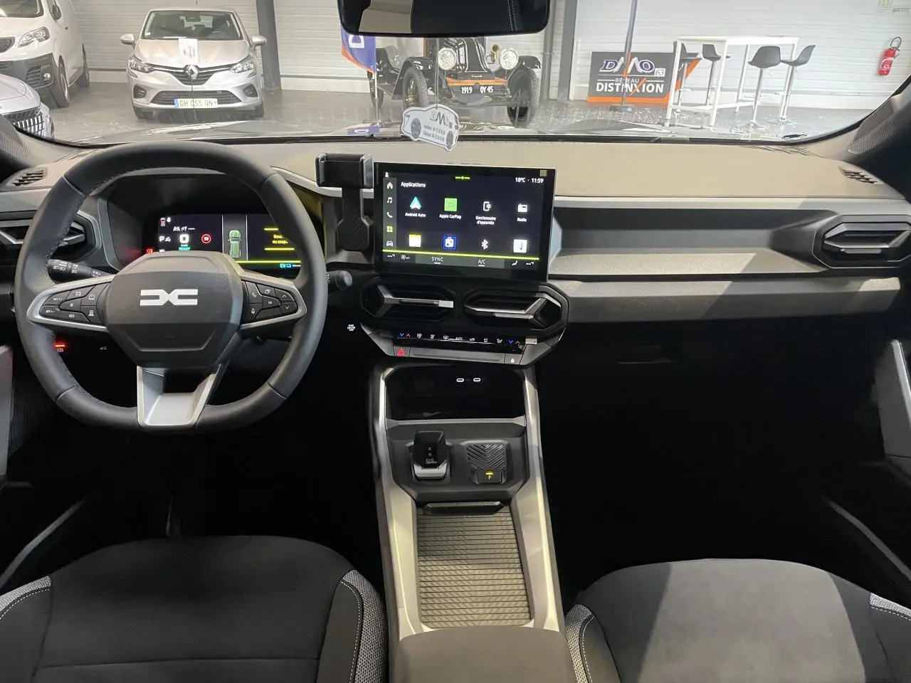 Vue intérieure avant du tableau de bord et volant du Dacia Bigster gris schiste avec écran tactile central et commandes au volant.