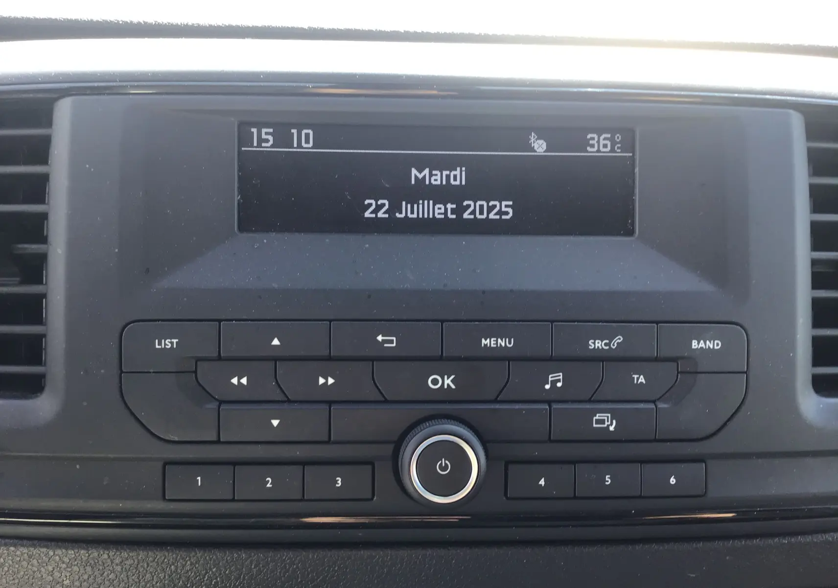 Affichage central de la radio de l'Opel Vivaro blanc 2023, avec écran digital indiquant la date et la température.