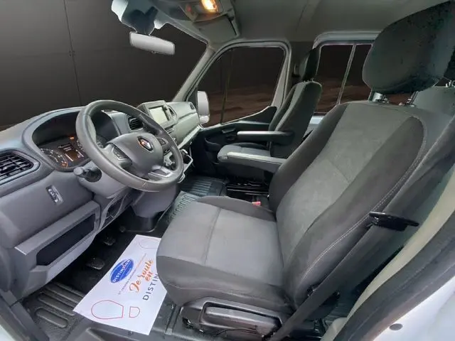 Vue intérieure côté conducteur du Renault Master Double Cabine 2022, sièges tissu noir avec accoudoirs et tableau de bord moderne.