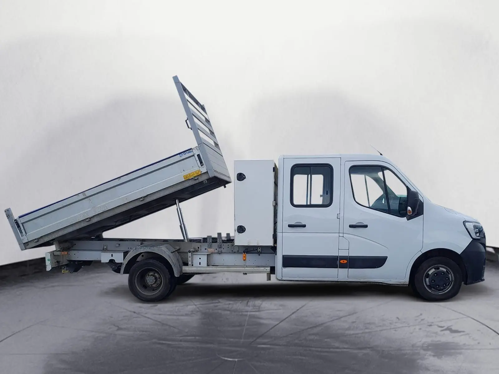 Renault Master blanc en vue de profil côté droit, benne arrière relevée avec coffre latéral blanc.