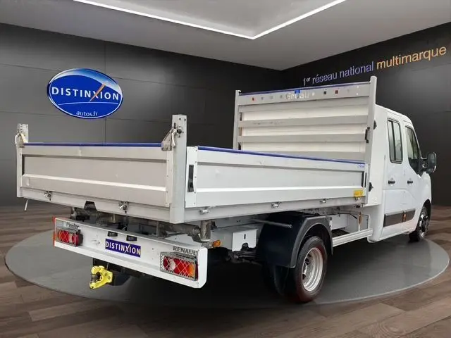 Vue 3/4 arrière droite d’un Renault Master blanc double cabine avec benne et coffre, en intérieur showroom.