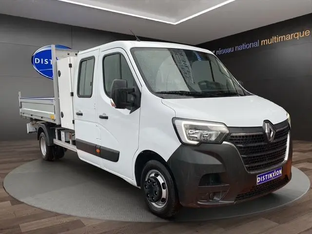 Vue 3/4 avant droit d’un Renault Master blanc double cabine avec benne et coffre, intérieur visible par les vitres.