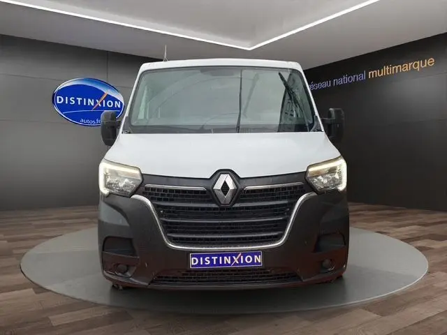 Vue frontale d’un Renault Master blanc avec calandre noire et phares allumés dans un showroom.
