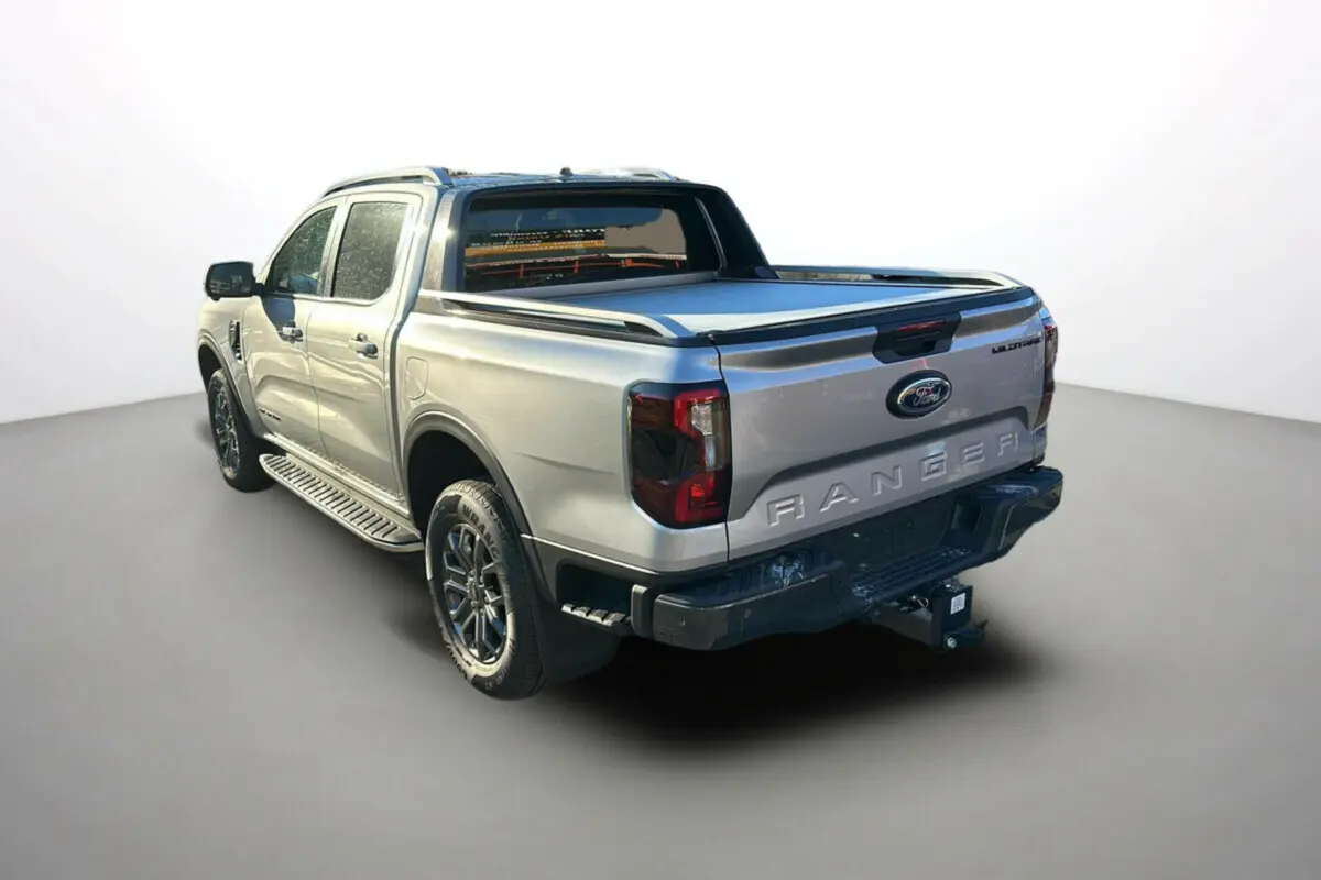 Ford Ranger 2.0 205 Wildtrak Plus gris iconic, vue 3/4 arrière droit, avec arceau sport et attelage visible.
