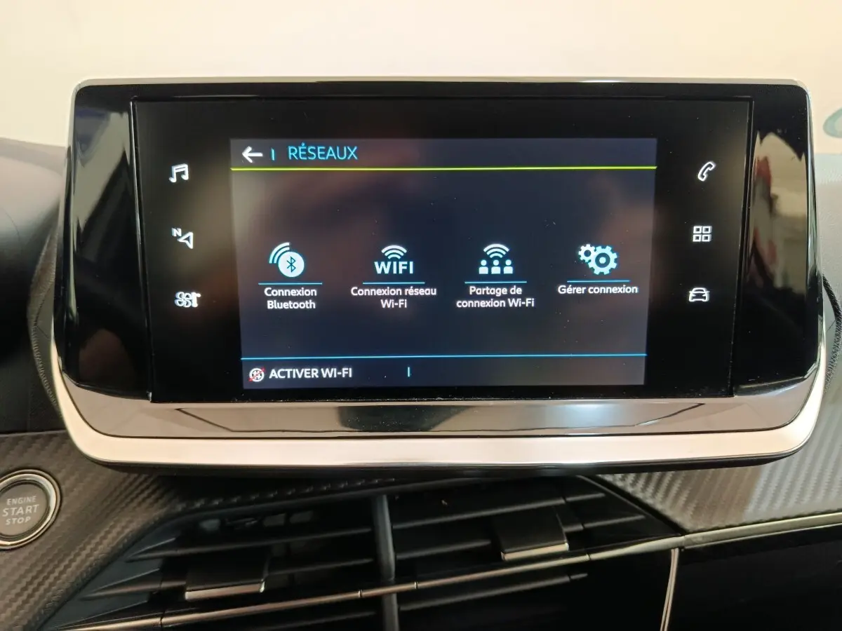 Écran tactile central de la Peugeot 208 électrique blanc, affichant les options de connexion réseau Wi-Fi et Bluetooth.
