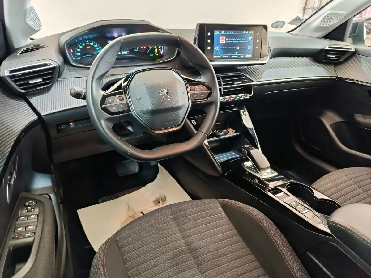 Vue intérieure côté conducteur du tableau de bord et volant cuir de la Peugeot 208 électrique Active Business R 2022.