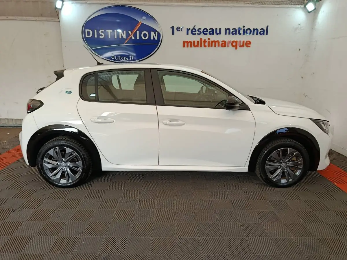 Vue de profil côté gauche d'une Peugeot 208 électrique Active Business R blanche avec jantes alliage et détails noirs autour des roues.