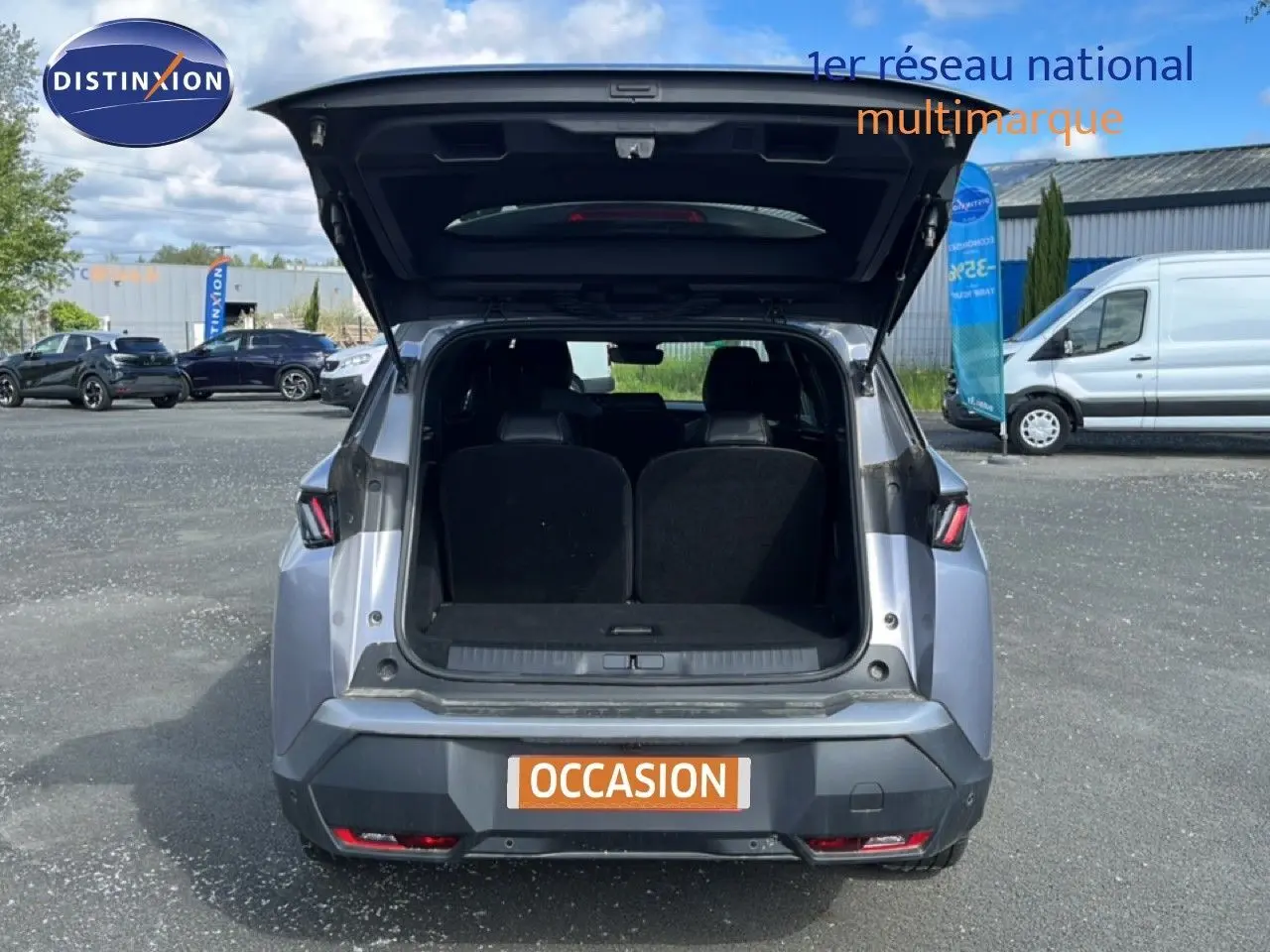 Vue arrière d’un Peugeot 5008 gris Artense métal 2025 avec coffre ouvert sur parking extérieur.