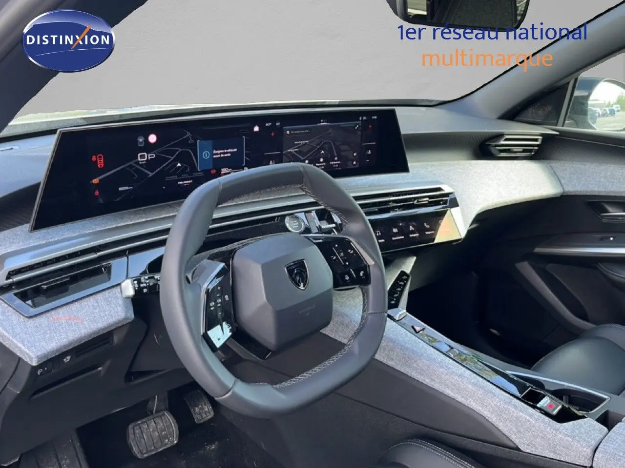 Vue intérieure côté conducteur du Peugeot 5008 Hybrid 2025, mettant en valeur le tableau de bord numérique et le volant cuir gris.