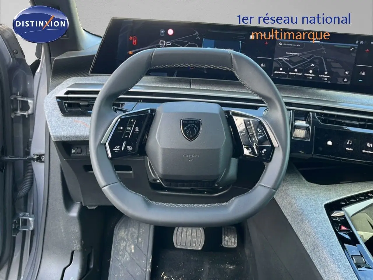 Vue intérieure centrée sur le volant gris cuir du Peugeot 5008 Hybrid 2025 avec tableau de bord numérique et écran tactile.