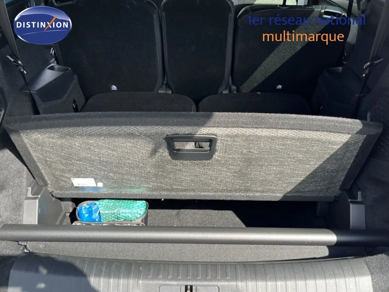 Vue plongeante sur le coffre ouvert d’un Peugeot 5008 gris Artense, montrant le compartiment de rangement sous la tablette.