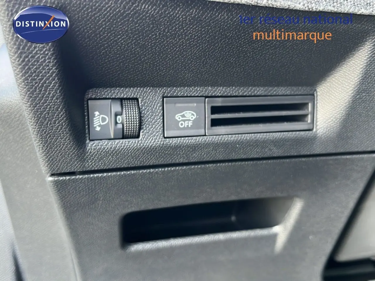 Détail intérieur montrant les commandes de réglage des phares et la ventilation sur Peugeot 5008 gris Artense 2025.