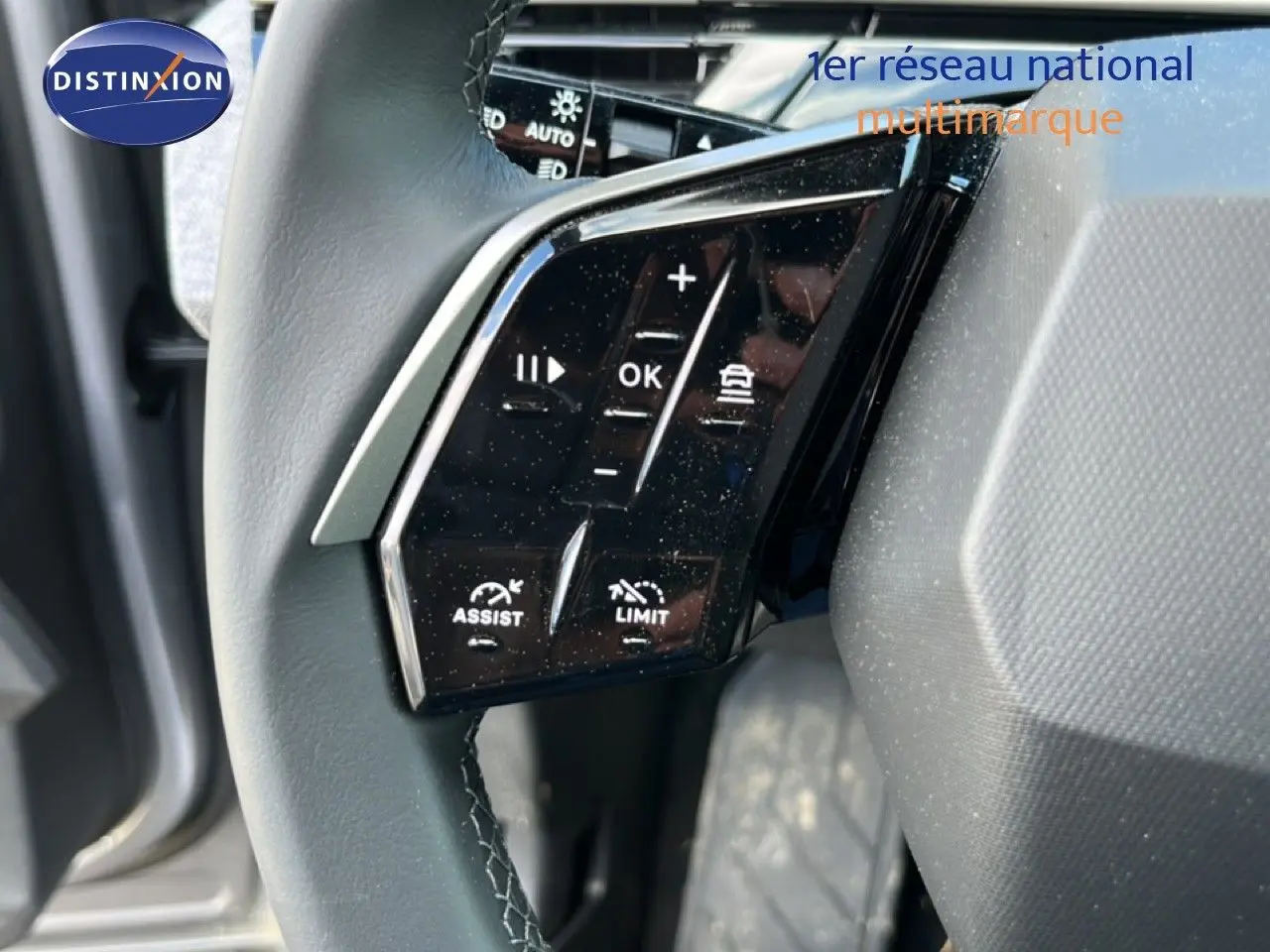 Gros plan sur les commandes gauche du volant du Peugeot 5008 gris Artense, boutons de régulateur et assistant visibles.