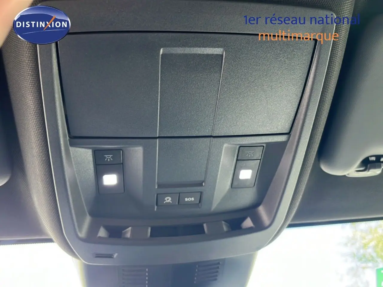 Vue en contre-plongée du panneau de commandes au plafond intérieur du Peugeot 5008 gris Artense métal, avec boutons d’éclairage et SOS.