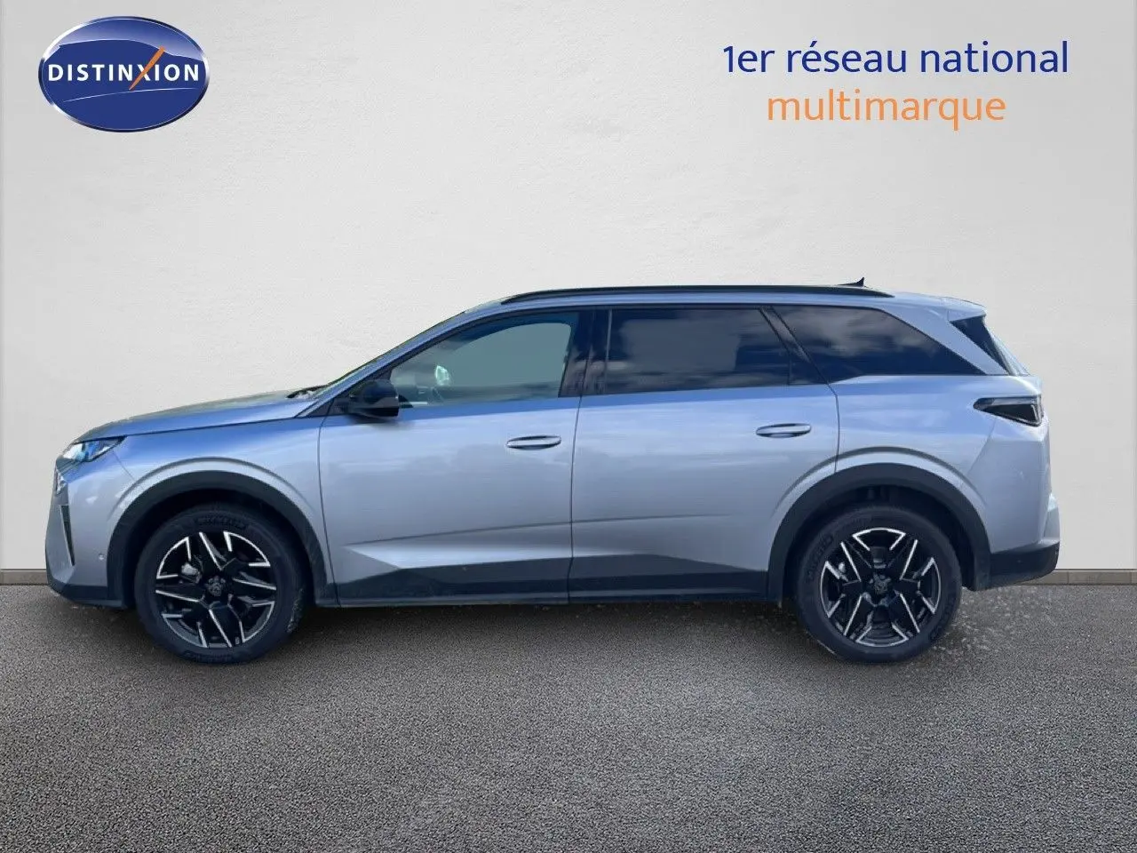 Profil droit du Peugeot 5008 Hybrid gris Artense métallisé, avec jantes noires et toit panoramique visible.