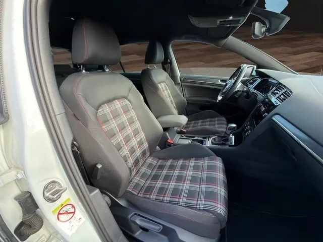 Vue intérieure côté conducteur d'une Volkswagen Golf GTI Performance 2019 avec sièges tissu à motif écossais et surpiqûres rouges.