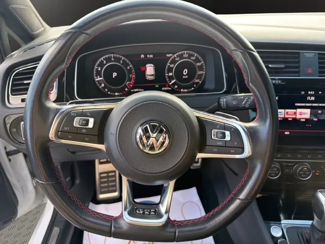 Vue intérieure centrée sur le volant cuir et alu avec coutures rouges de la Volkswagen Golf GTI Performance blanche de 2019.