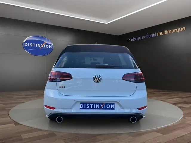 Vue arrière d’une Volkswagen Golf GTI Performance blanche, avec double sortie d’échappement et toit noir contrasté.