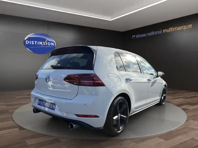 Vue 3/4 arrière droite d’une Volkswagen Golf GTI Performance blanche, avec jantes noires et feux arrière teintés.