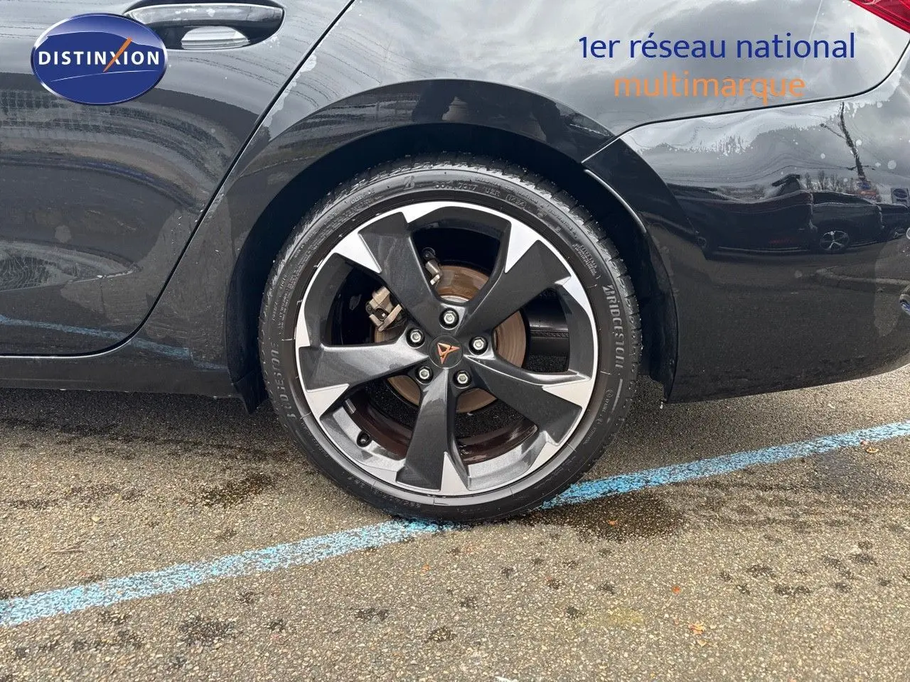 Gros plan sur la roue arrière droite d'une CUPRA LEON ST noire Midnight Metal avec jante biton distinctive.