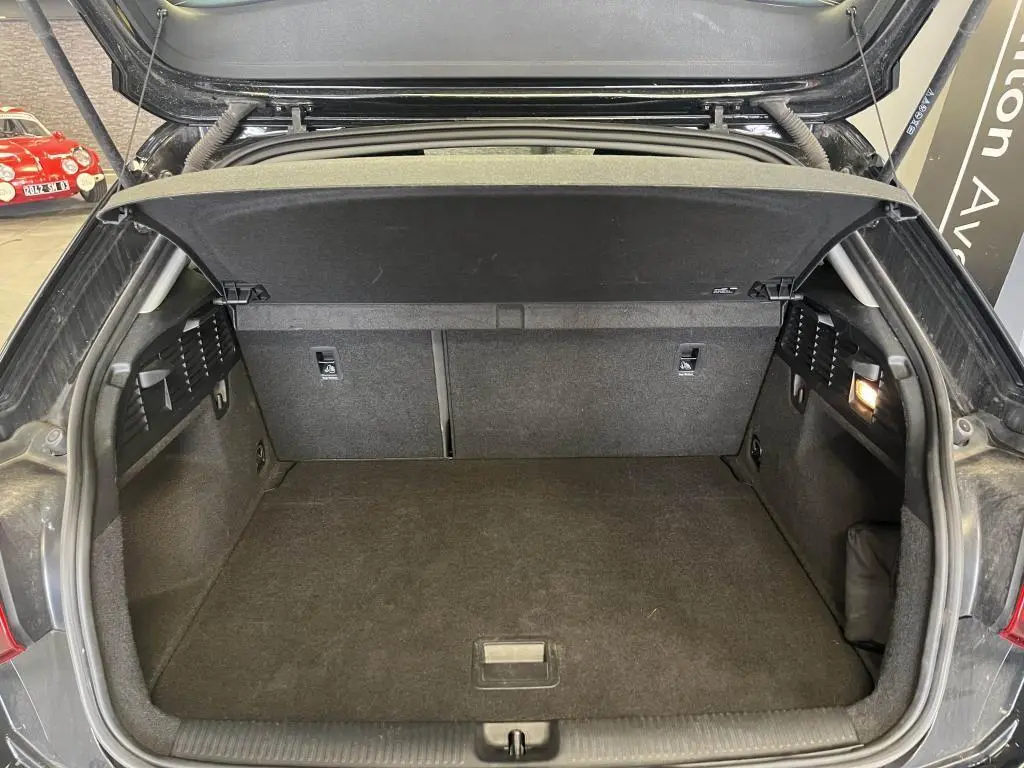 Coffre ouvert vu de l'arrière d'un Audi Q2 noir 2022, intérieur spacieux et tapis de sol sombre.
