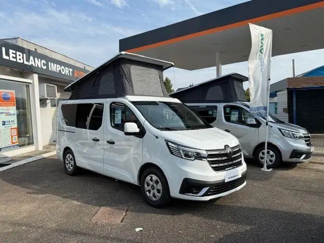Vue 3/4 avant gauche du Renault Trafic blanc glacier avec toit relevable noir sur parking de concession.