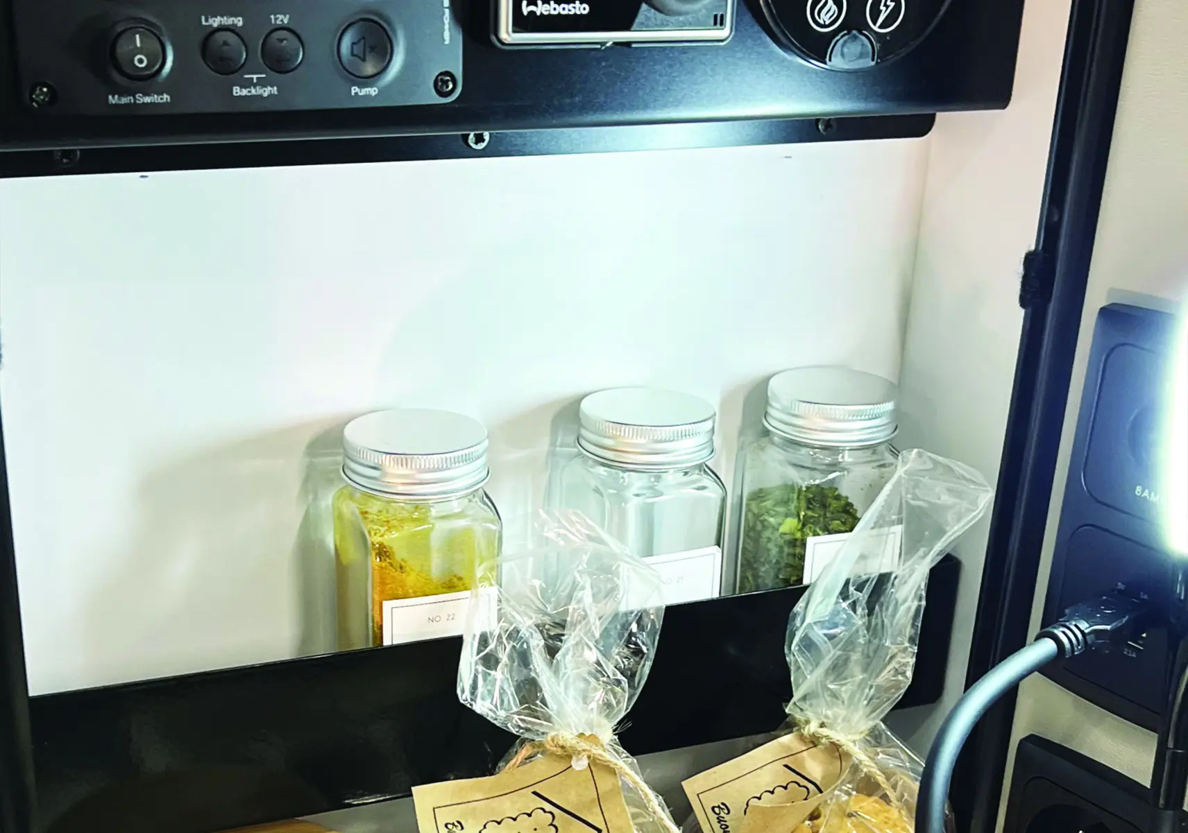 Panneau de contrôle Webasto et rangement d'épices avec snacks dans la cuisine du Renault Trafic Fourgon blanc glacier.
