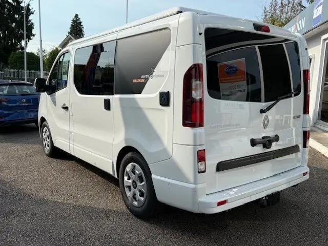 Vue 3/4 arrière droite du Renault Trafic Fourgon blanc glacier avec vitres teintées et logo Antilope Van sur la porte latérale.