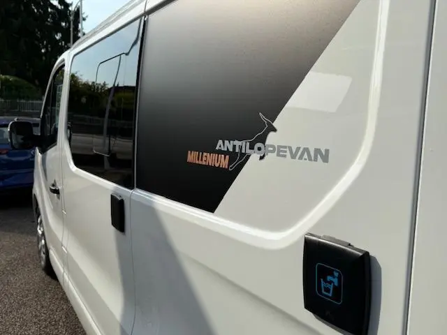 Vue latérale gauche du Renault Trafic Fourgon blanc glacier avec logo Antilope Van Millenium sur la porte coulissante.