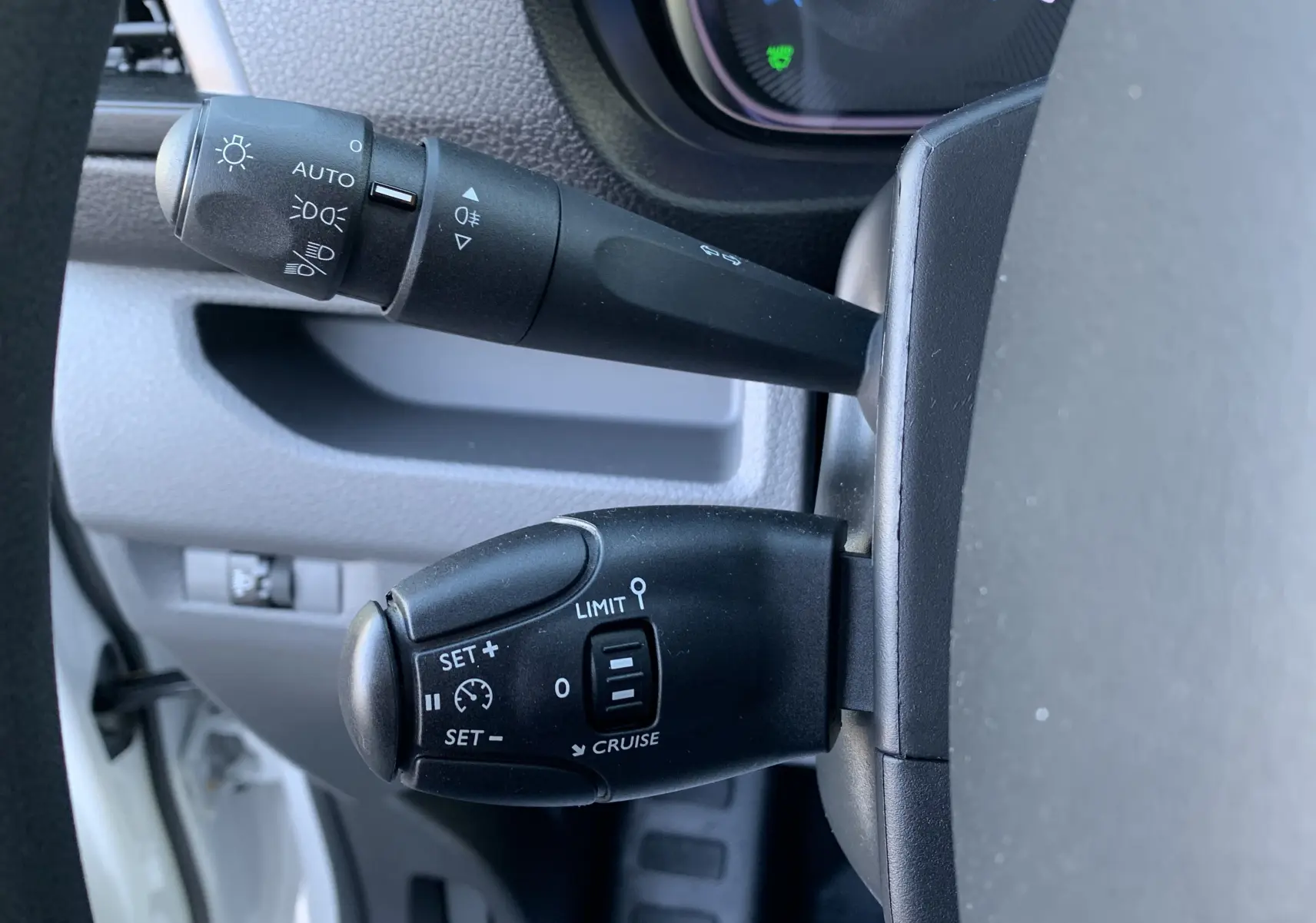 Gros plan sur les commandes de régulateur de vitesse et des phares dans un FIAT Scudo Combi blanc, intérieur côté gauche.