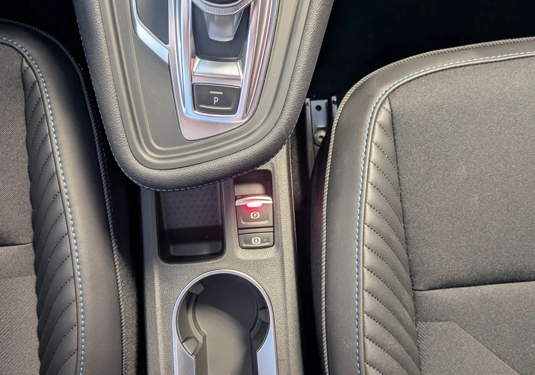Vue plongeante sur la console centrale noire étoilé du Renault SYMBIOZ avec levier de vitesses automatique et sièges en tissu noir.