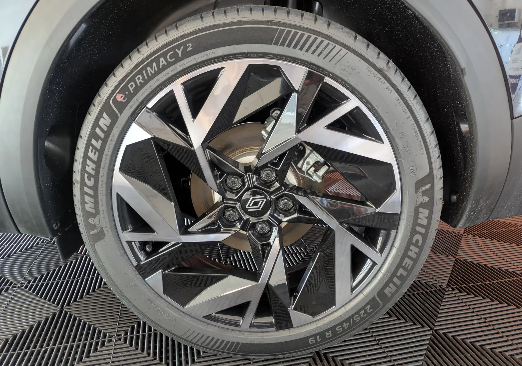 Gros plan sur la jante 19 pouces Elixir bicolore noir et argent du Renault Symbioz noir étoilé, pneu Michelin visible.