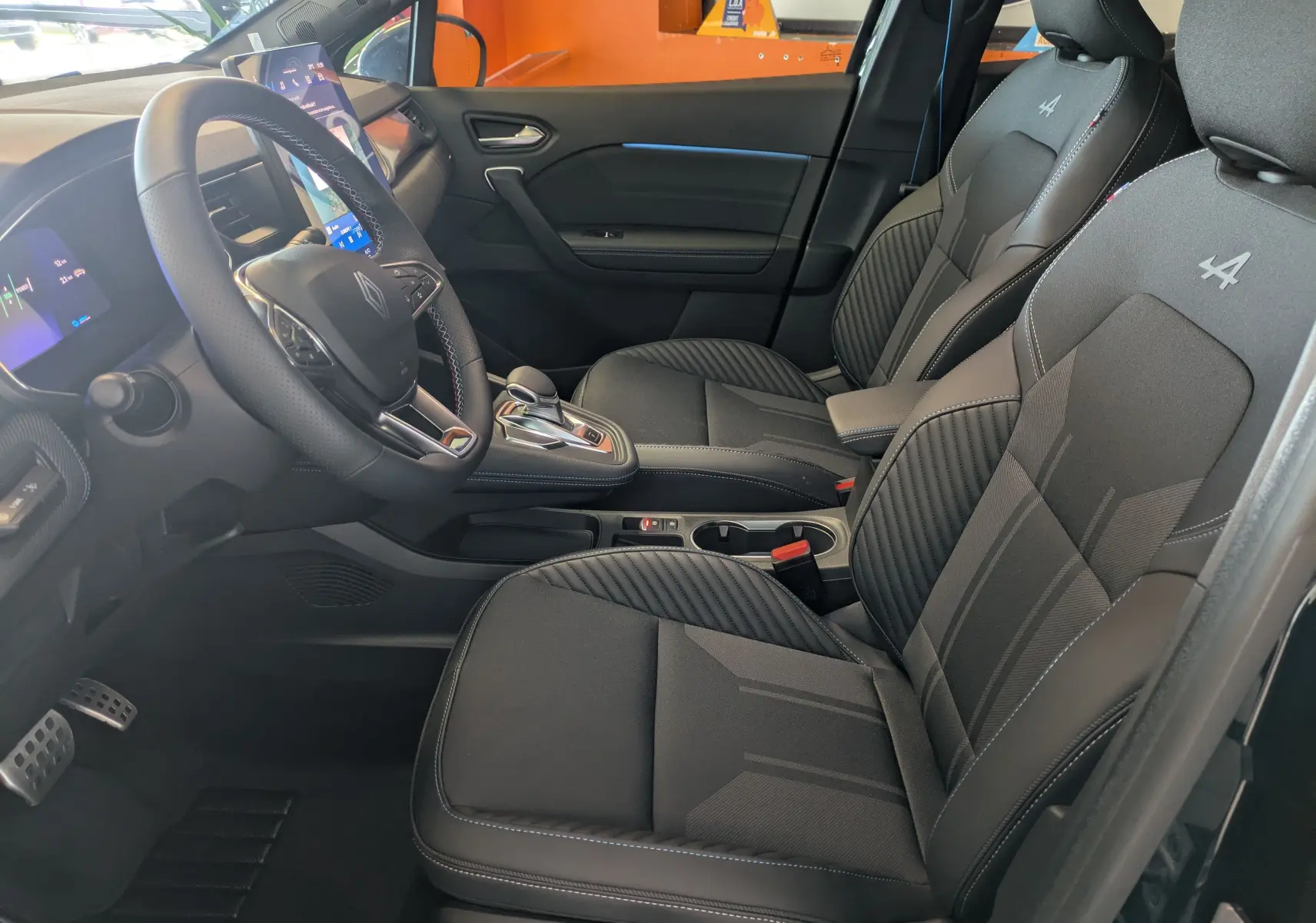 Vue intérieure côté conducteur de la Renault SYMBIOZ E-Tech noir étoilé, sièges et volant cuir avec logo Alpine brodé.