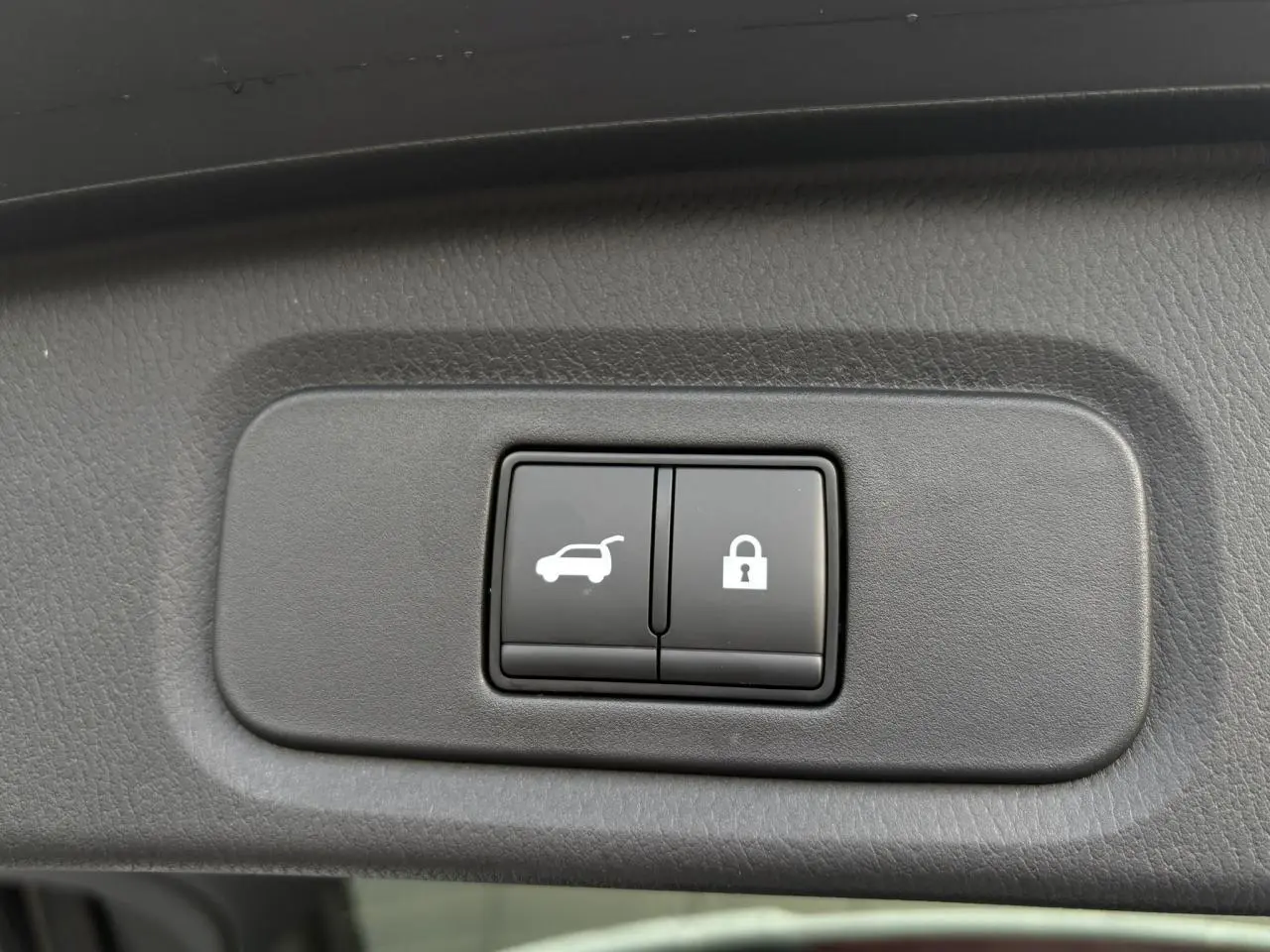 Gros plan sur les boutons d'ouverture électrique du hayon et de verrouillage du Nissan Qashqai blanc nacré, intérieur du hayon.