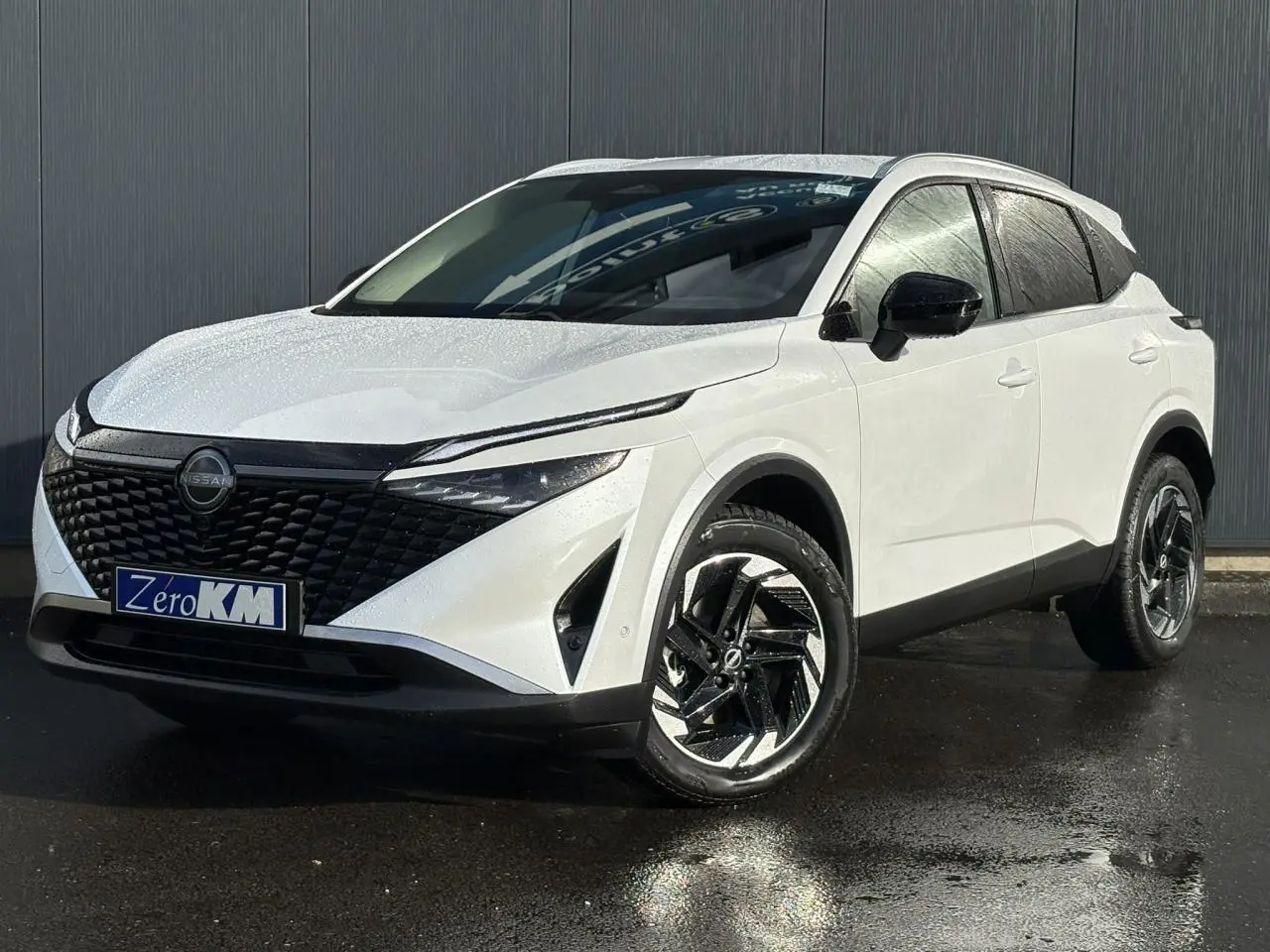 Vue 3/4 avant droit du Nissan Qashqai blanc nacré avec calandre noire et jantes alliage bicolores.