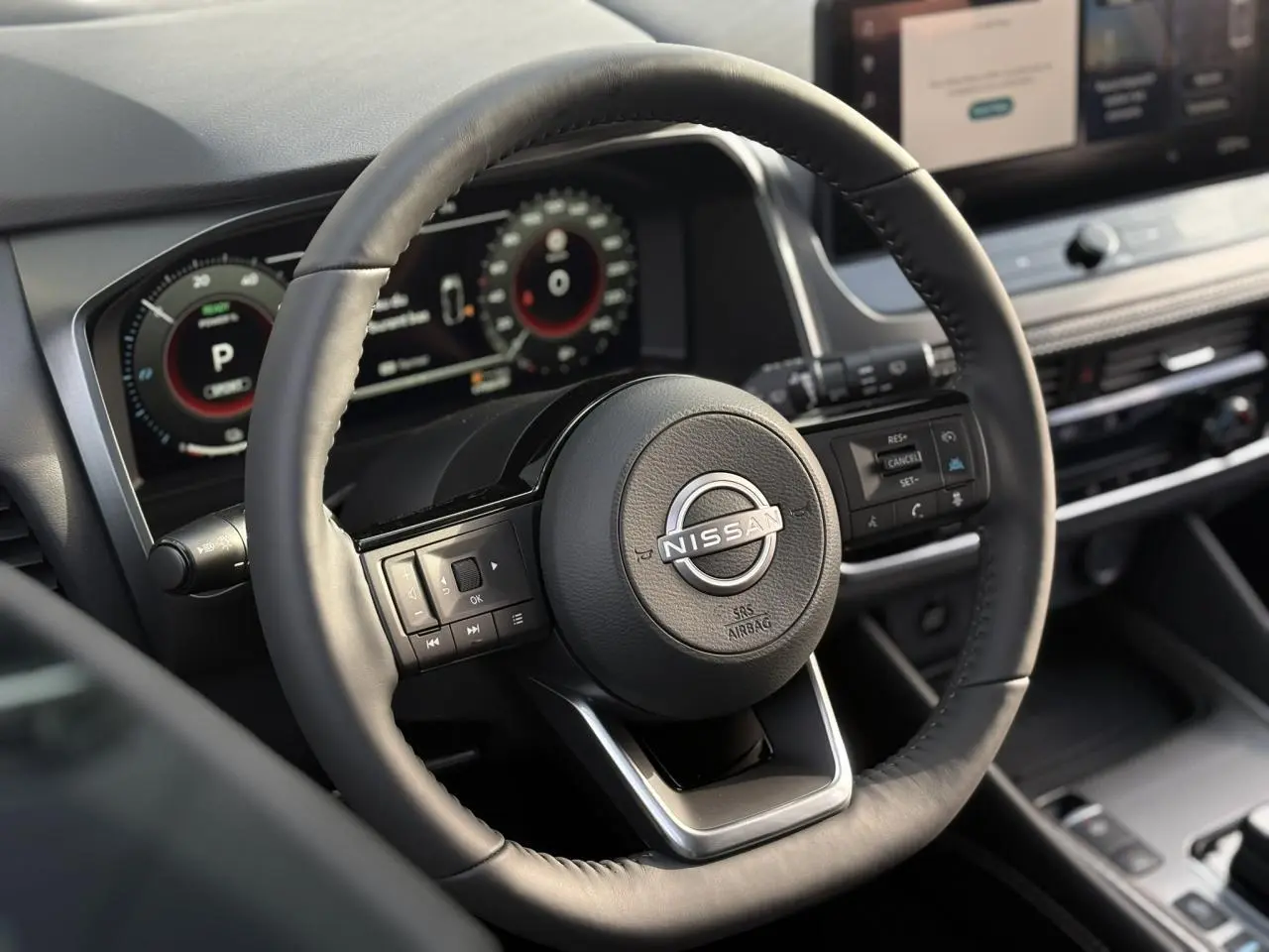 Vue rapprochée du volant cuir noir et du tableau de bord numérique du Nissan Qashqai blanc nacré 2025.