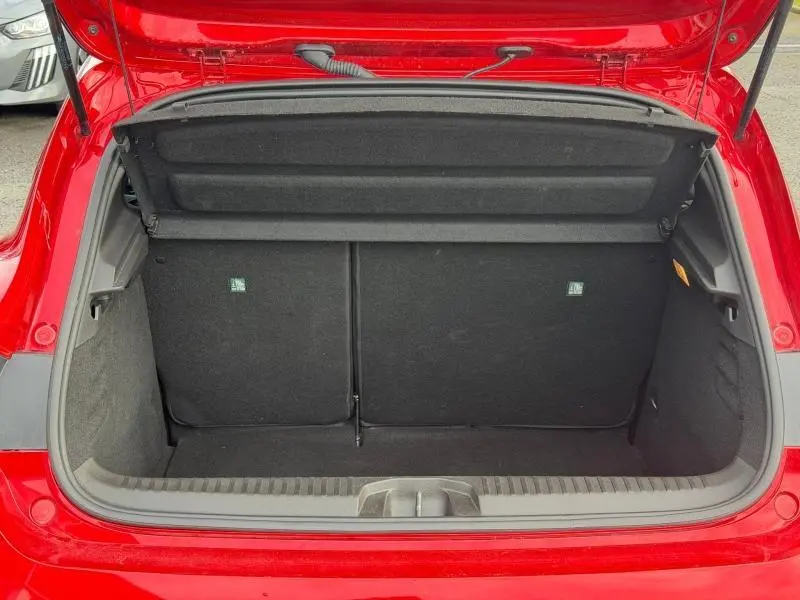 Coffre ouvert vu de l'arrière d'une Renault Clio 1.0 TCe 90ch Techno rouge flamme, montrant l'espace de chargement vide.