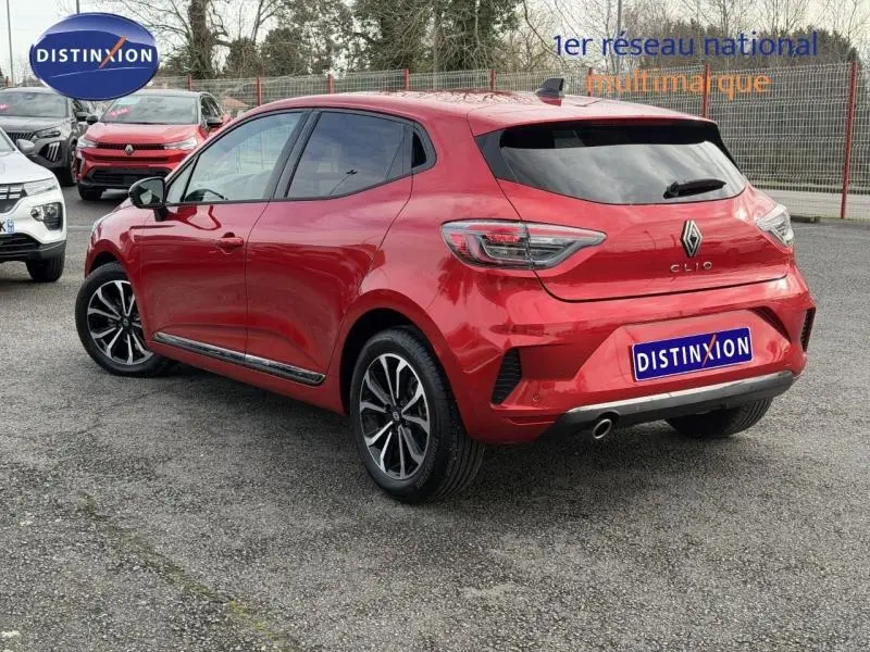 Vue 3/4 arrière droite d'une Renault Clio 1.0 TCe 90ch Techno rouge flamme avec jantes alliage et vitres teintées.