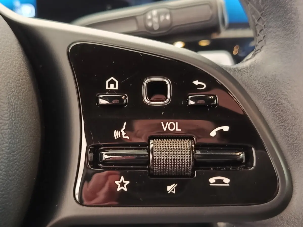 Gros plan sur les commandes noires du volant cuir multifonctions de la Mercedes Classe A 180 Business Line.