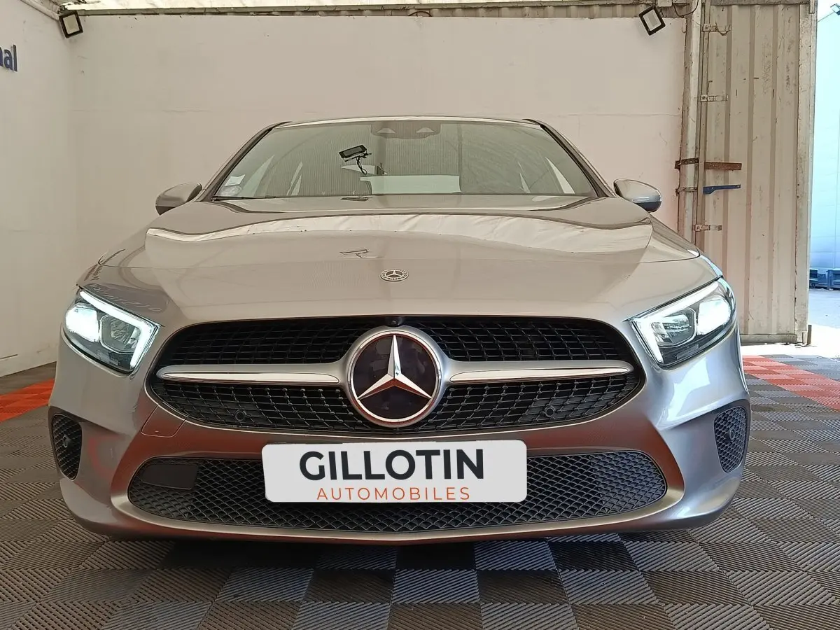 Vue frontale d'une Mercedes Classe A 180 Business Line gris clair avec phares LED allumés dans un garage.