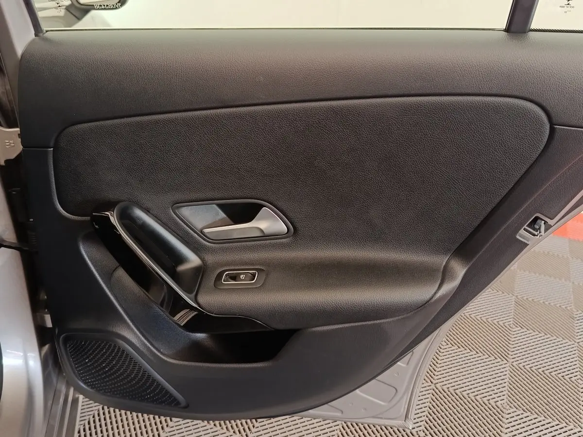 Vue intérieure de la porte avant gauche noire avec poignée argentée et bouton de commande de vitre sur Mercedes Classe A gris clair.