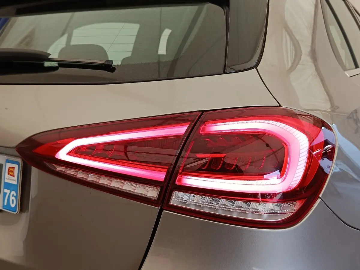 Gros plan sur le feu arrière droit allumé d’une Mercedes Classe A gris clair, avec partie de la lunette arrière visible.